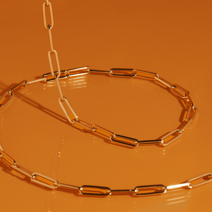 Flatlay Model. Close up of gold chain necklace on orange background