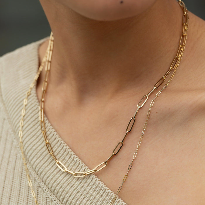 Lifestyle Model. Close up of woman wearing two chain necklaces with beige sweater