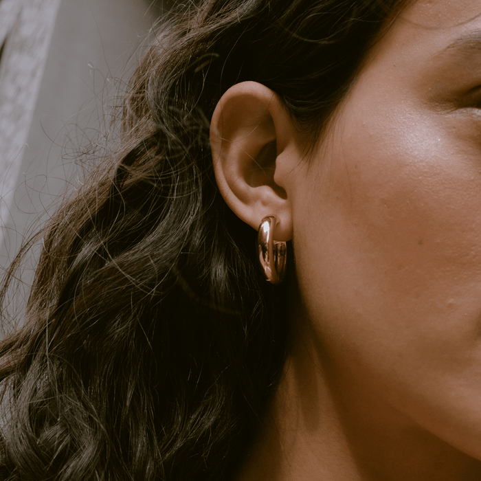 Model. Close up of woman with brown hair wearing gold hoop earring