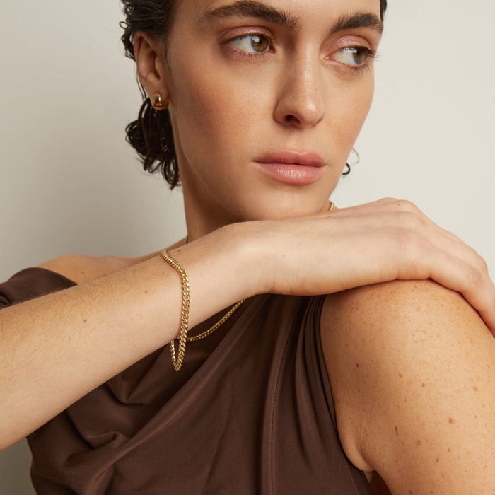 Model. Woman wearing gold jewelry against a neutral background
