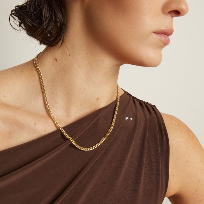 Model. Gold chain necklace worn by a person with a plain background