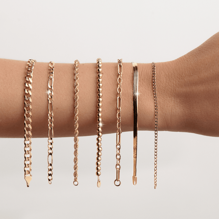 Lifestyle Model. Close up of woman's arm with 7 gold chain bracelets hanging on it