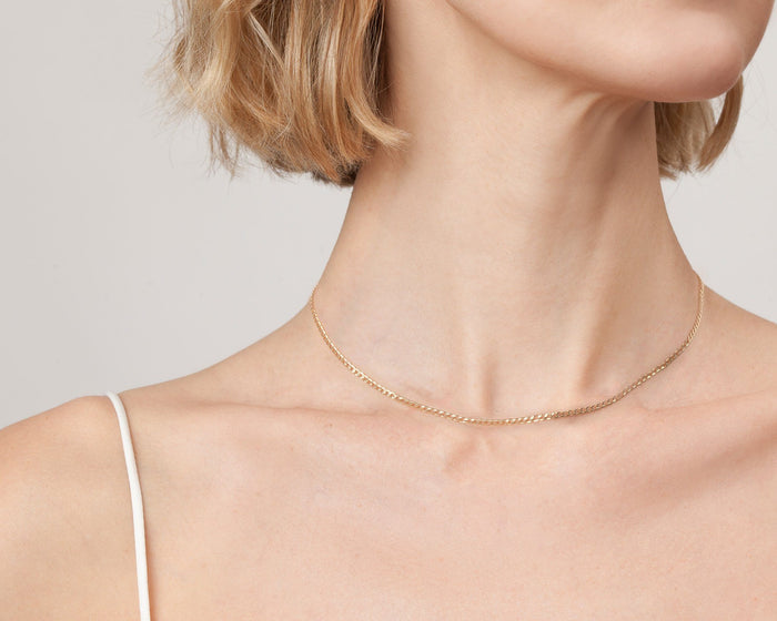 Model. Close up of woman wearing gold chain necklace on white background
