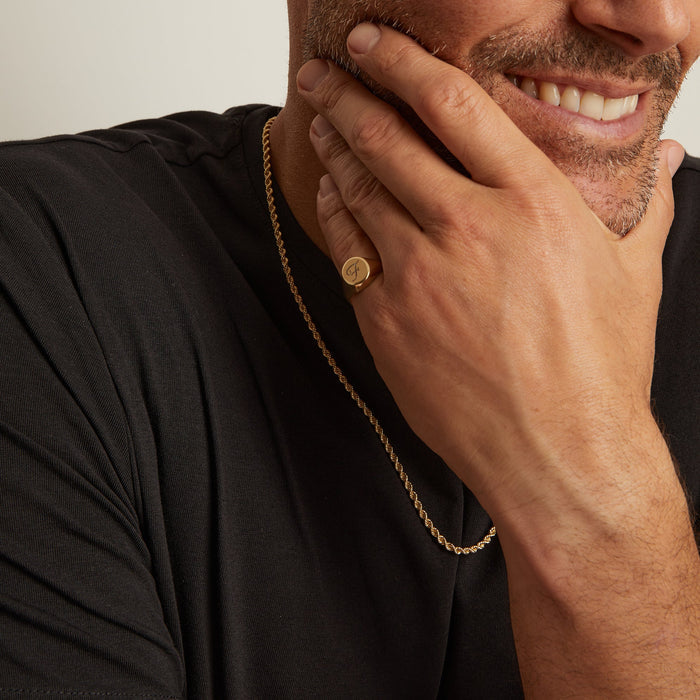Model. Man wearing a gold necklace with a plain background