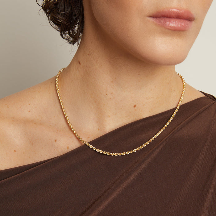 Model. Gold necklace worn by a person with a neutral background