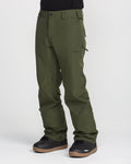 A person wearing olive green Volcom Men’s Freakin Snow Chino Pants and black boots stands against a plain white background. The men’s snow pants feature a side pocket and are constructed from a durable, waterproof, and breathable material.