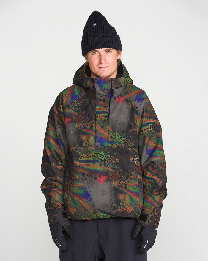 A person wearing the Volcom Men’s Hossegor 20K Pullover—a colorful, patterned jacket made from a recycled V-Science shell—along with black gloves and a black beanie, stands facing the camera against a plain light background.