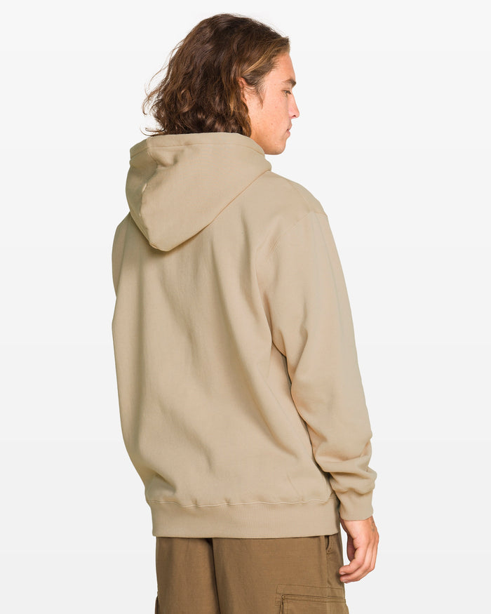 A person with wavy brown hair, wearing the Volcom Men's Stone Coast Pullover and brown pants, stands facing away from the camera against a plain white background.