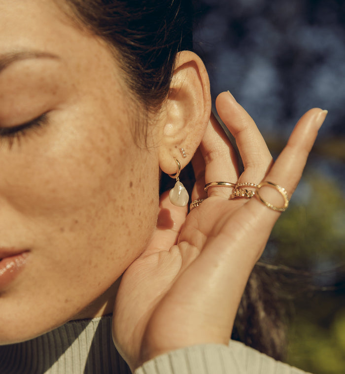 Lifestyle Model. A close-up lifestyle shot of a woman wearing various rings and earrings outdoors.