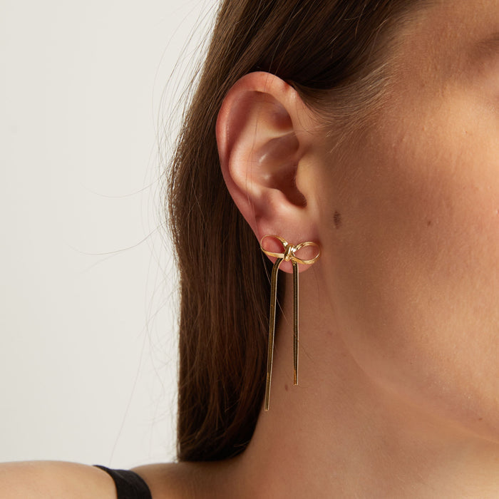 Model. Close up of woman wearing bow earrings.