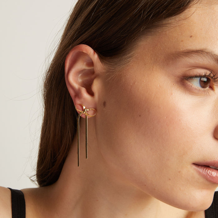 Model. Close up of woman wearing bow earrings.