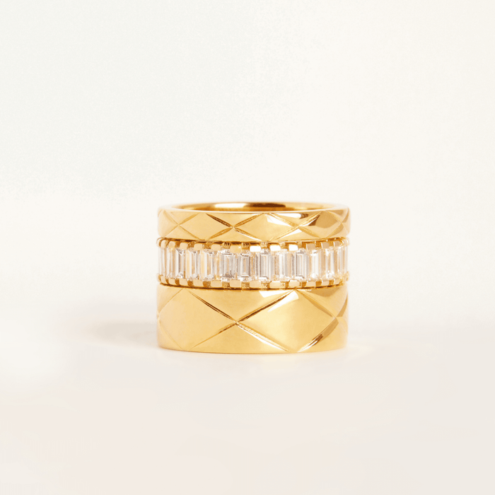 Lifestyle Model Close-up of three stacked rings—two gold quilted bands and a diamond baguette band—on a white background