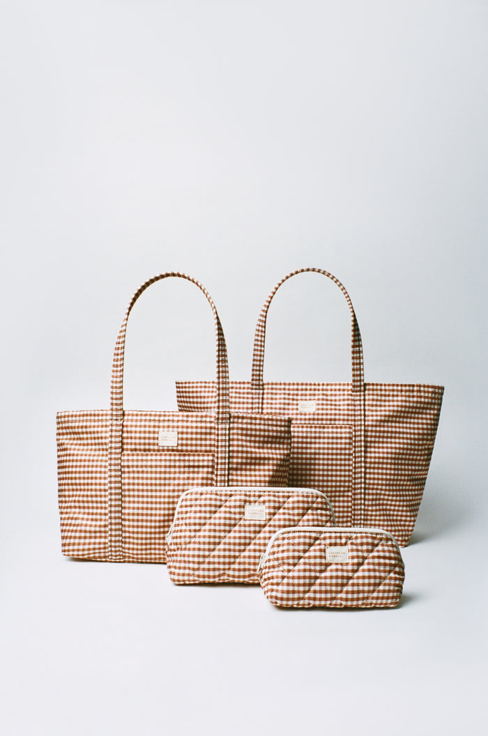 Dina Brown Gingham Travel Tote in brown gingham nylon, Mira Brown Gingham Everyday Tote in brown gingham nylon, Frances Brown Gingham Cosmetic Pouch, and Georgette Brown Gingham Mini Cosmetic Pouch.
