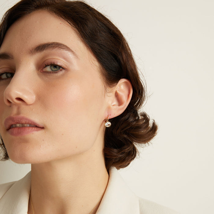 Model Close-up of a woman wearing gold earrings with a neutral background