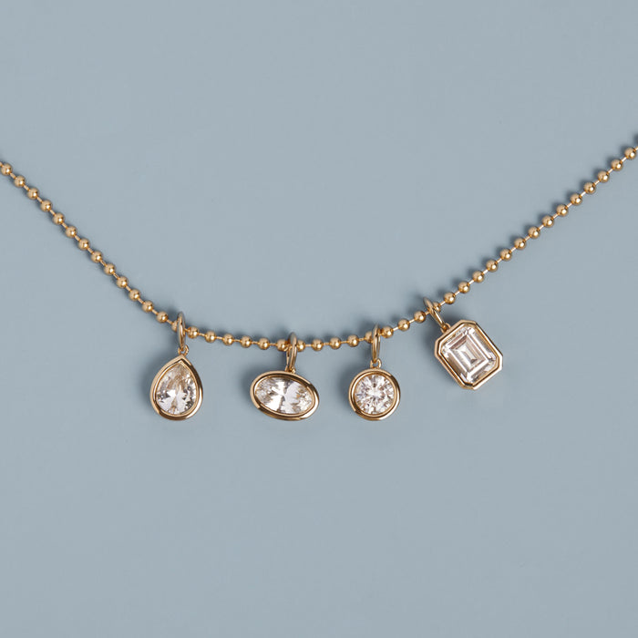 Model. Gold necklace with four diamond pendants on a light blue background