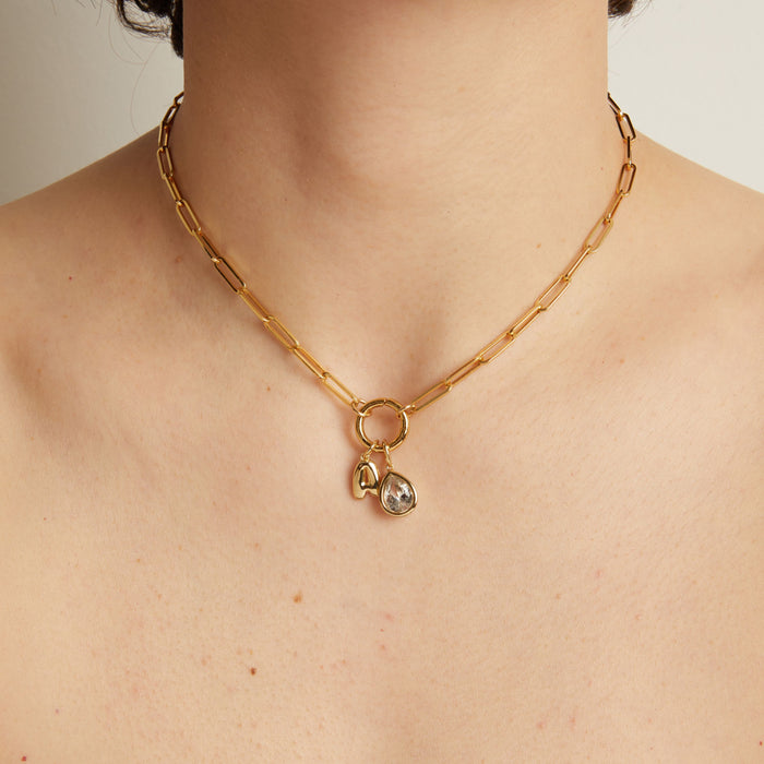 Model. Gold necklace with a pendant on a person's neck against a neutral background