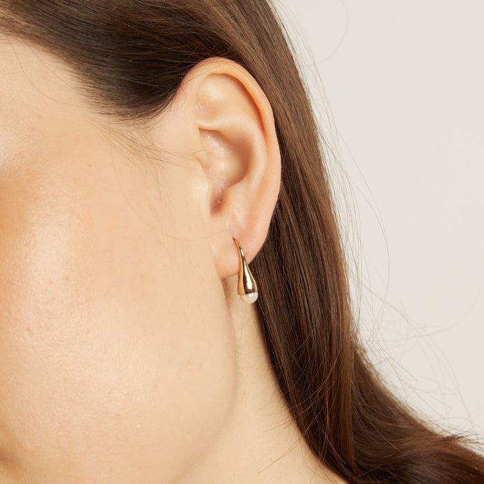 Model Gold teardrop earring worn by a person with a neutral background