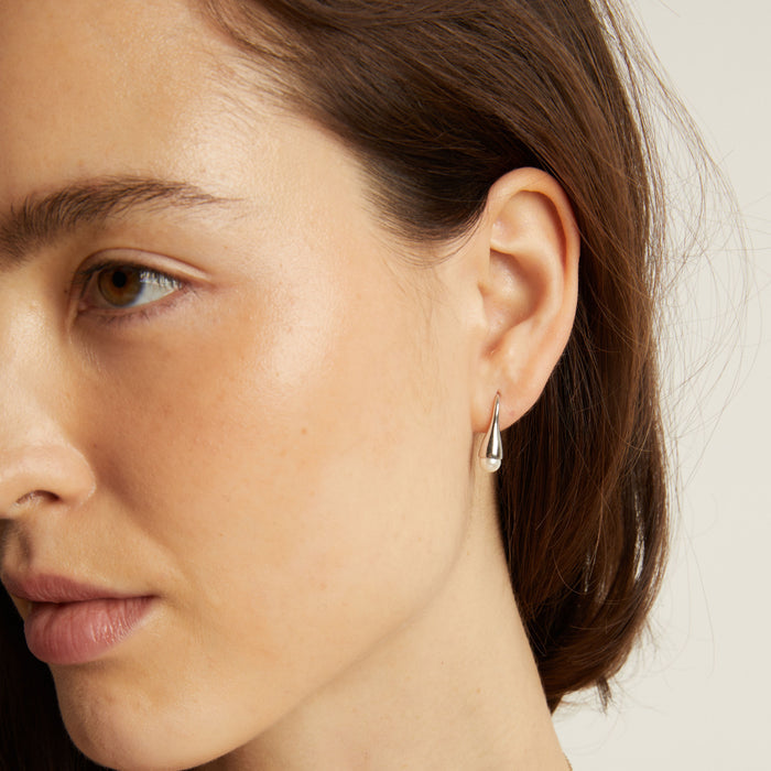 Model Close-up of a woman wearing a silver earring with a neutral background