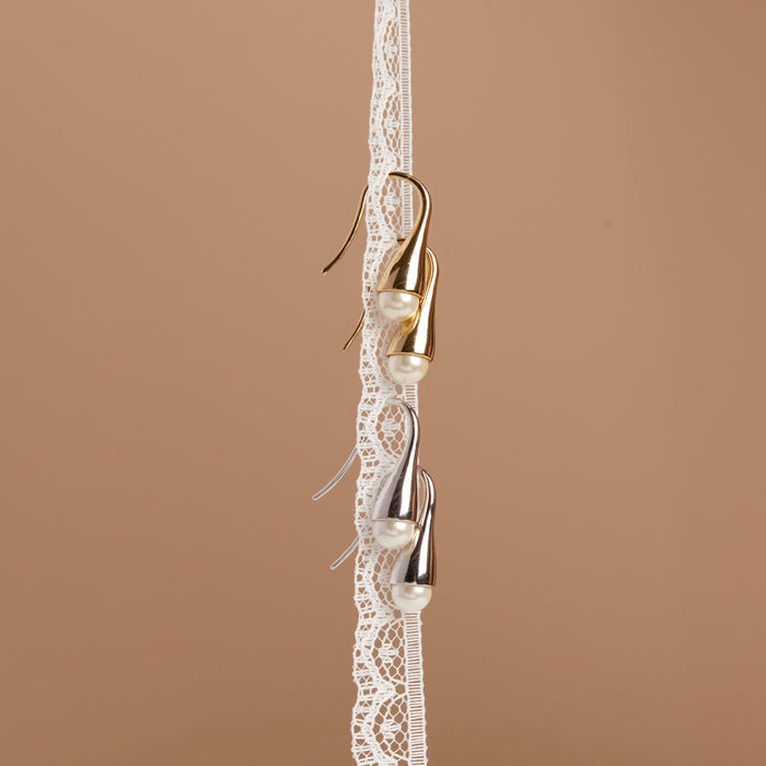 Model Gold earrings on a lace ribbon against a brown background