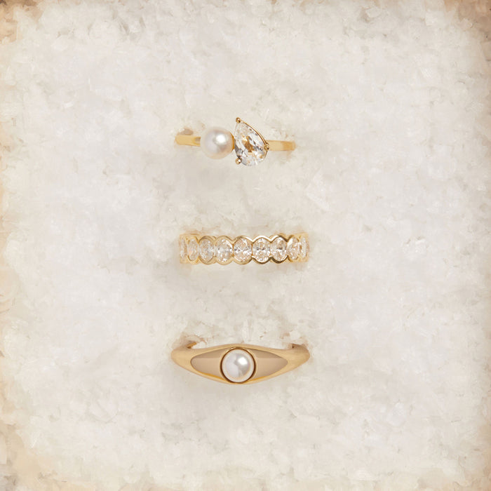 ModelSet of gold rings with pearls and crystals on a soft beige background
