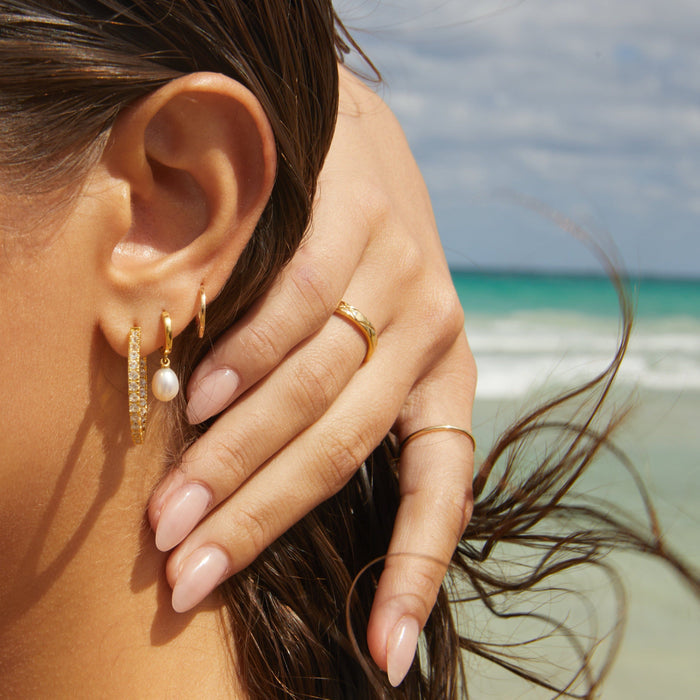 Model.  side profile of woman wearing different earrings at the beach