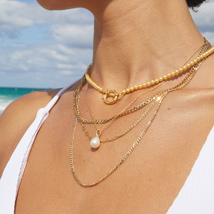 Model.  close up of woman wearing multiple necklaces at the beach