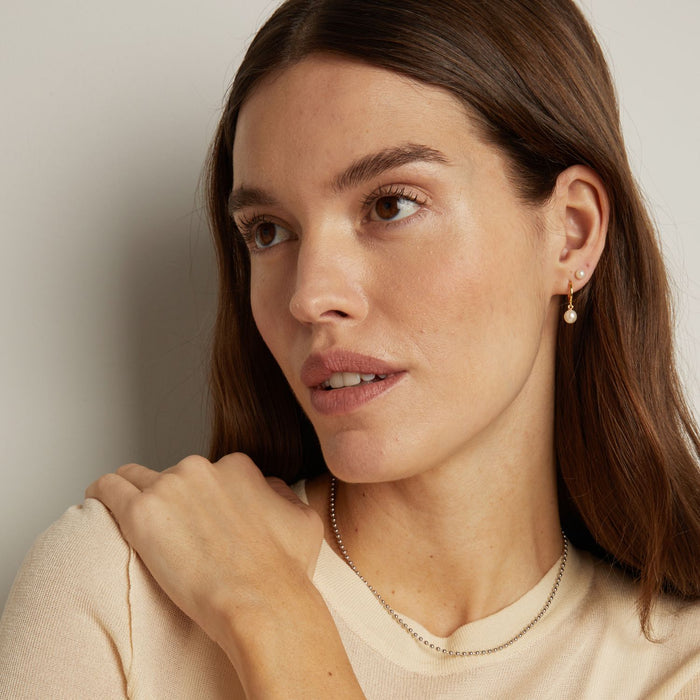 Model. Woman wearing a necklace and earrings against a neutral background