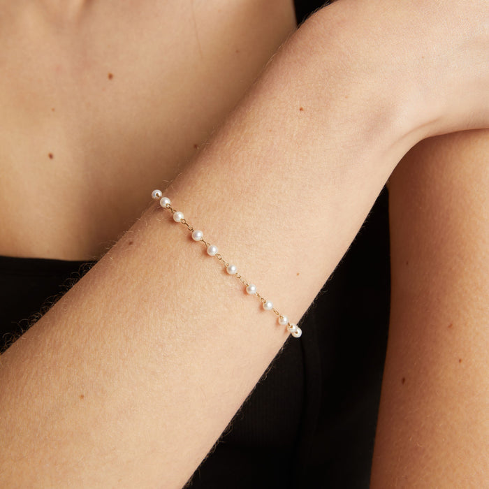 Close up of a pearl bracelet on woman with neutral background.