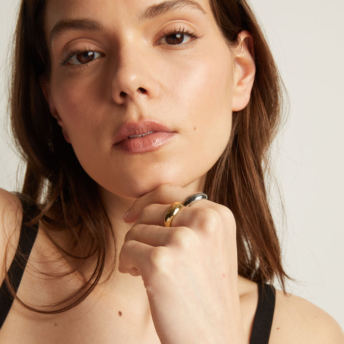 Model. Close up of a woman with gold and silver rings on her finger, touching her face.