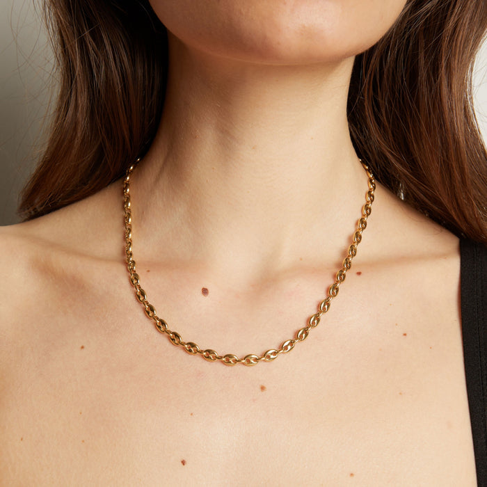 Gold chain necklace on woman in black tank top. Model