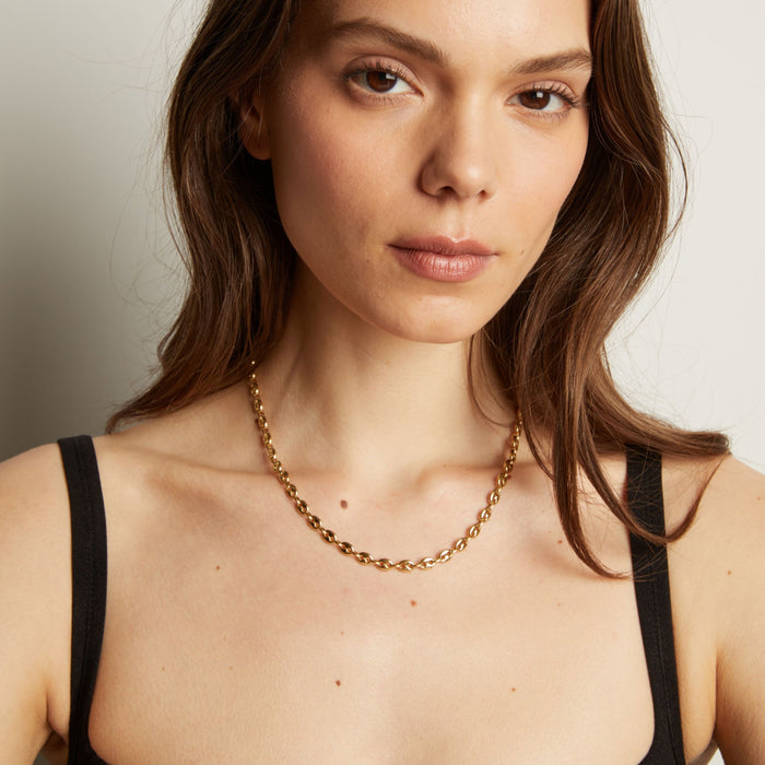 Gold chain necklace on woman in black tank top. Model