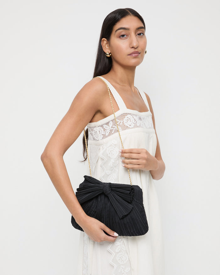 Rayne Black Bow Clutch in black pleated organza fabric and Poppy Lace Dress in white cotton.