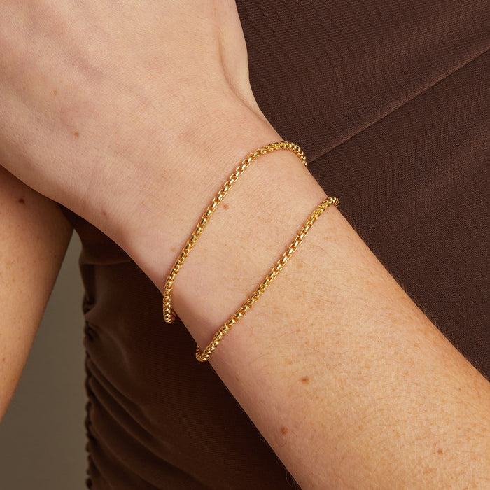 Model. Gold bracelet on a wrist with a neutral background