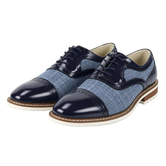 A pair of men's cap-toe oxford shoes featuring a mix of sapphire blue patent leather and a textured blue-gray woven fabric. The shoes have dark navy laces, a white midsole, and a brown outsole, shown against a plain white background.