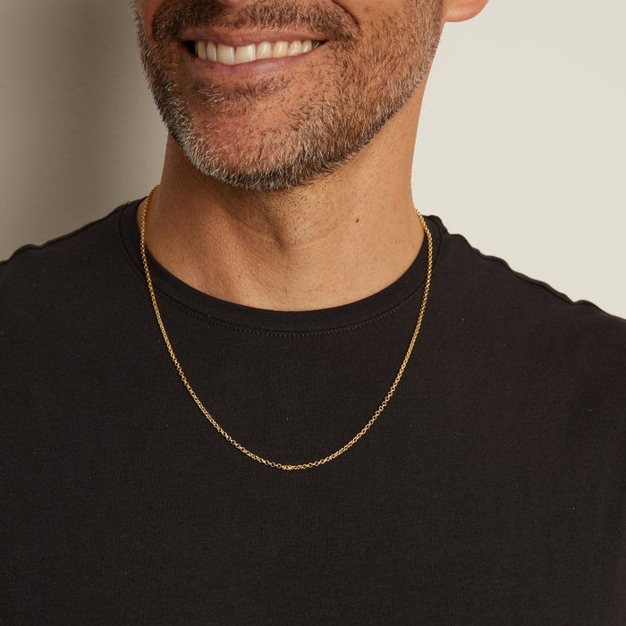 Model. Man wearing a gold chain necklace against a neutral background