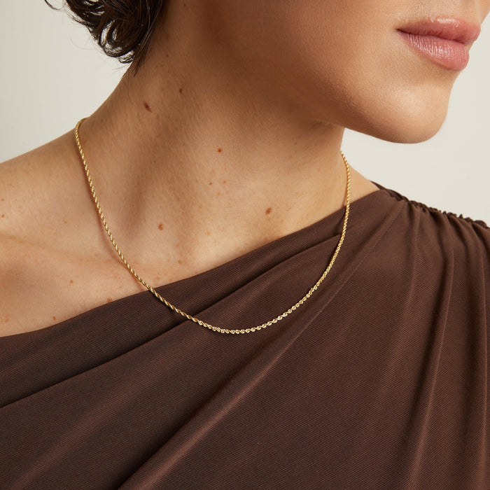 Model. Gold necklace on a person wearing a brown garment