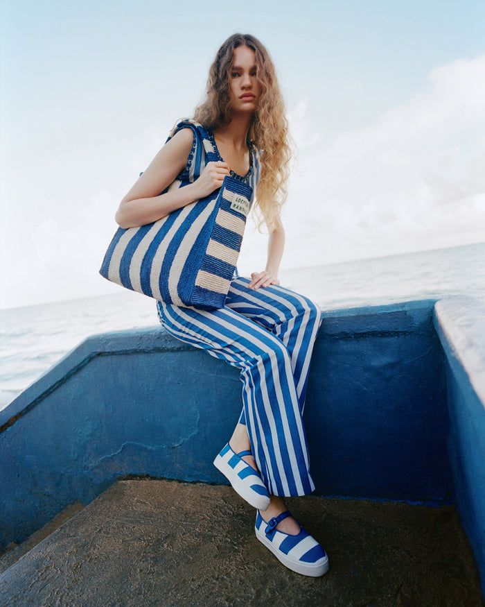 Sol Blue Striped Crochet Beach Tote in blue and cream striped raffia, Veda Top in blue and cream striped cotton, Pasha Trouser in blue and cream striped cotton, and Cooper Blue Striped Mary Jane Sneaker.