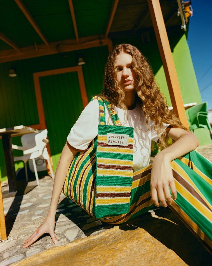 Harly Tee in white cotton, Pasha Trouser in green/yellow/brown striped cotton-linen, and Sol Green/Yellow Crochet Beach Tote.