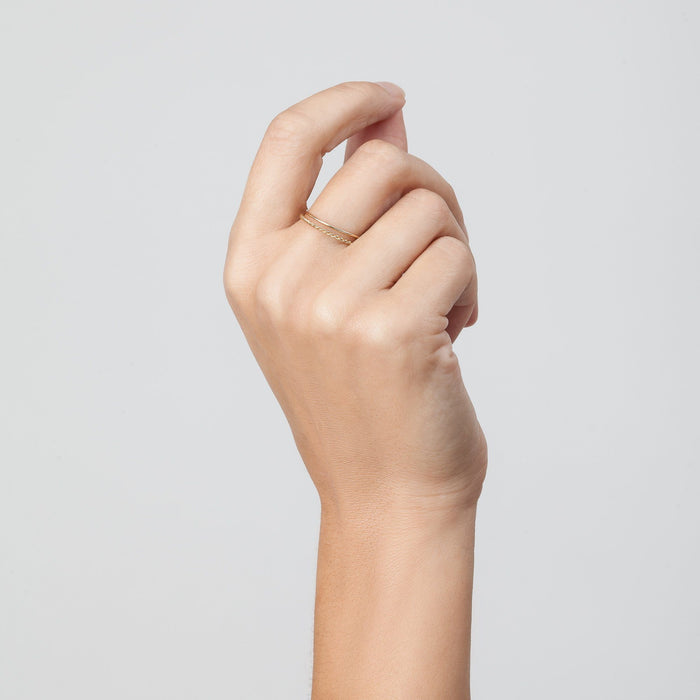 Model. Hand wearing a gold ring on a light gray background