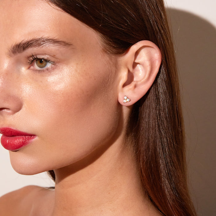 Model. Close-up of a woman wearing a diamond earring against a neutral background