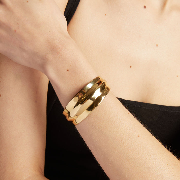 Model. Close up of a gold cuff bracelet.