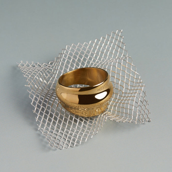 Model. Gold ring on a textured silver grid against a gray background