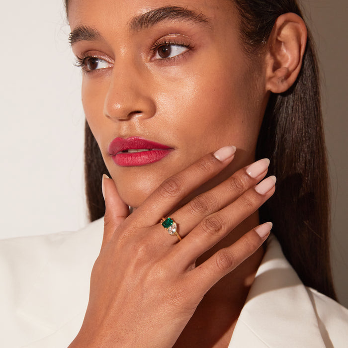 Model. Woman wearing a ring with a green gemstone on a neutral background