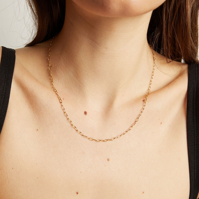 Model. Gold necklace on a person with a neutral background.