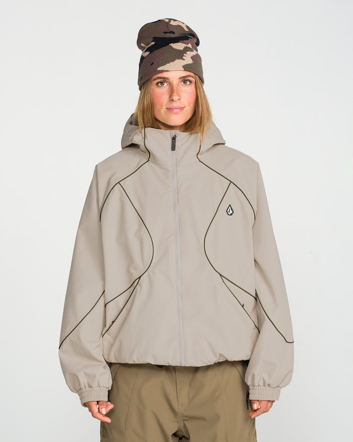 A person wearing the Volcom Unisex Liftline 20K Jacket in taupe with a baggy fit and black piping, paired with matching khaki pants and a brown camouflage beanie, stands against a plain white background facing forward with a neutral expression.