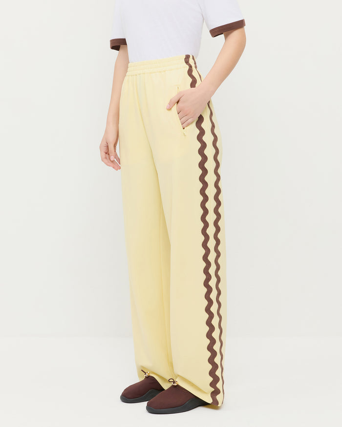 Venus Track Pant in butter yellow nylon, Harly Tee in white cotton, and Raina Dark Brown Mesh Flat.