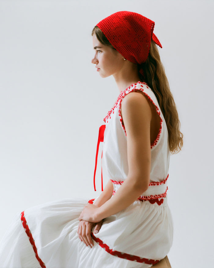 Viv Red Crochet Scarf in red crocheted cotton, Veda Top in white cotton with red details, and Aimee Skirt in white cotton with red details.