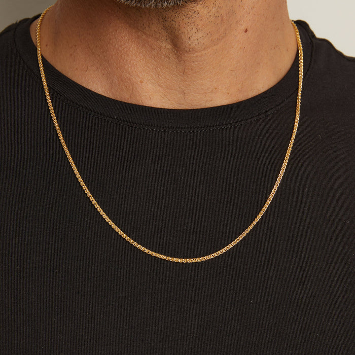 Model. Man wearing a gold chain necklace against a neutral background