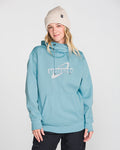 A person wearing a cream knit beanie and the Volcom Women’s Riding Hydro Pullover—with a drawcord hood and front pocket—stands against a plain white background, smiling slightly.