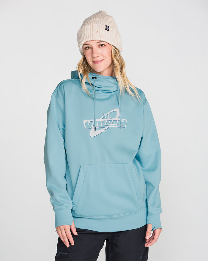 A person wearing a cream knit beanie and the Volcom Women’s Riding Hydro Pullover—with a drawcord hood and front pocket—stands against a plain white background, smiling slightly.